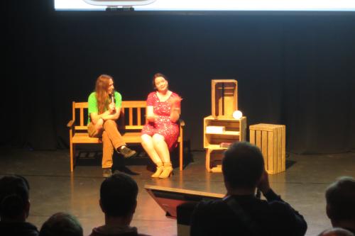 Marc and Sacha sitting on a bench on stage