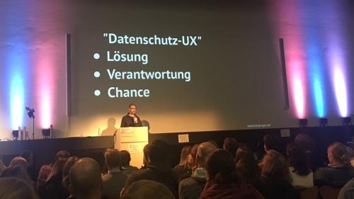 The author on a stage, with a slide: 'Datenschutz-UX: Lösung, Verantwortung, Chance'