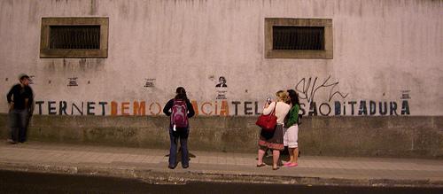 Four people standing in front of a graffiti on a wall