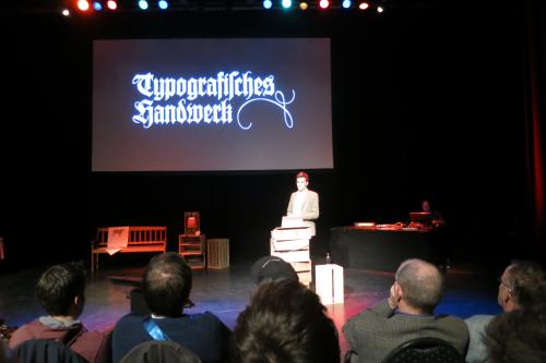 Frank on stage, with the words 'Typografisches Handwerk' typeset in an old font