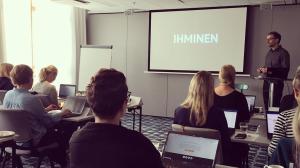 A seminar room with the author presenting a slide title with the Finnish word 'ihminen', which is 'human' in English