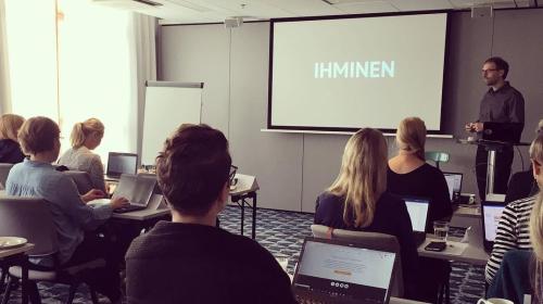 A seminar room with the author presenting a slide title with the Finnish word 'ihminen', which is 'human' in English