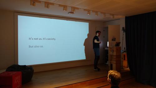 Oscar Braunert on stage, with a slide \