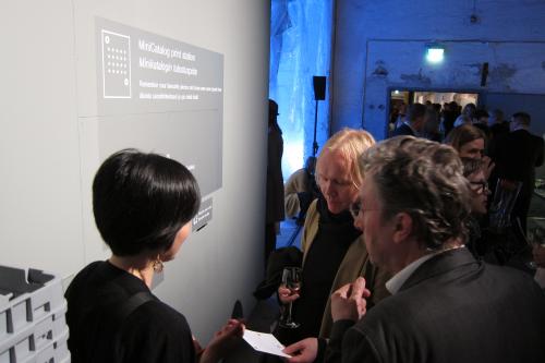 Exhibition visitors at the 'mini catalog print station' of the MoA 2012 exhibition