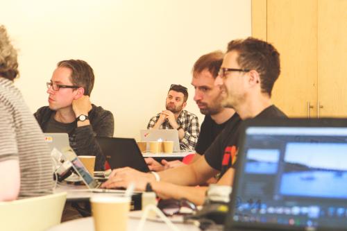 People with laptops sitting at tables and listening