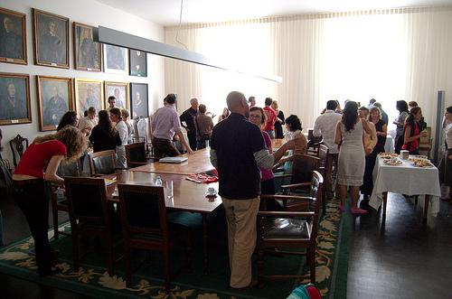 A big group of people standing in a room, engaged in conversations