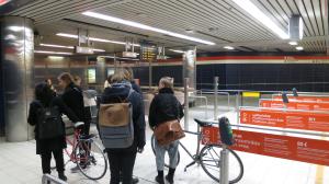 A group of five young people with two bicycles, entering the Hakaniemi subway station in Helsinki