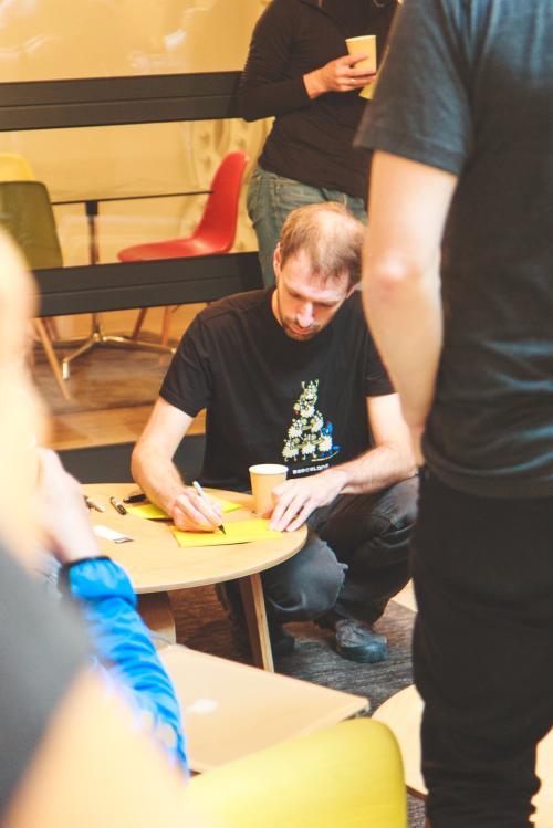 The author writing something on a big post-it notes, surrounded by others