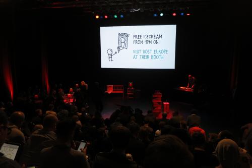 The audience sitting in front of the stage, with an announcement of free ice cream for the break on screen