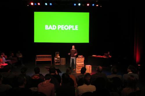 Tim on stage with a green slide carrying the words 'bad people' in capitals