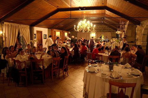A restaurant with round tables of eight people, some looking into the camera smiling